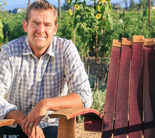 Artisan portrait at woodworking bench with whiskey barrel.