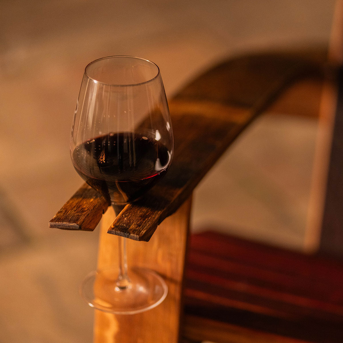 Close-up of the Cellr Wooden Adirondack Chair’s right arm showing the integrated stemmed wine glass holder made from wine barrel staves.