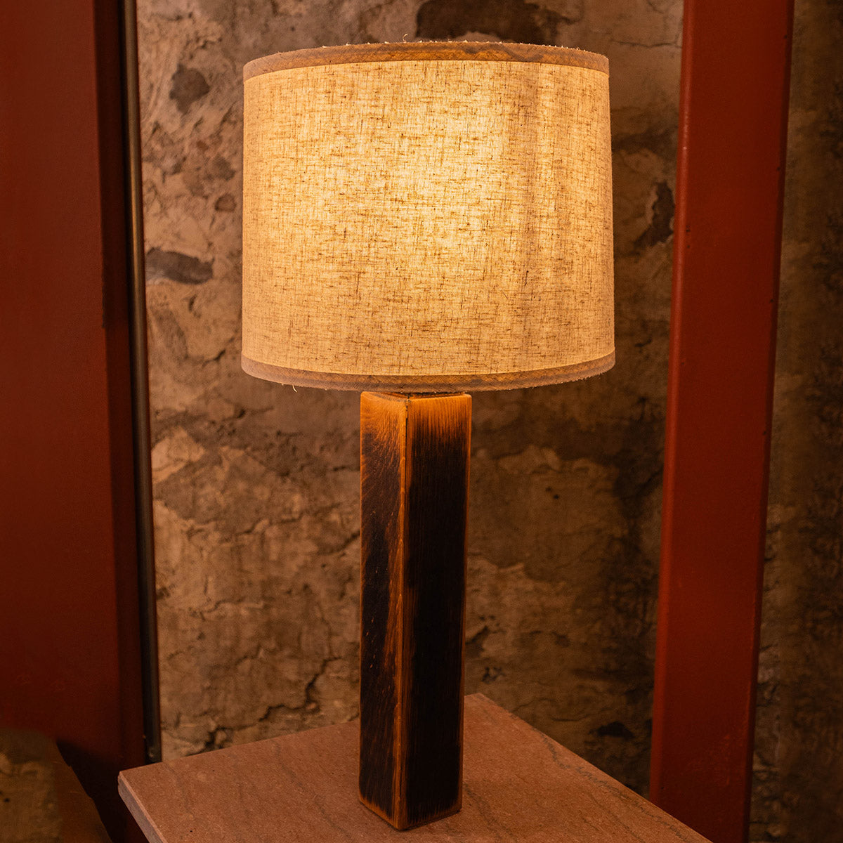 Close-up of the Charr Wooden Table Lamp showing the charred interior oak grain and the warm glow from the fabric lampshade.