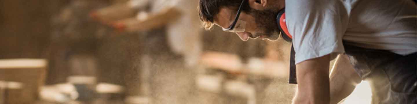 Focused craftsman sanding a live edge slab, highlighting the handmade quality of reclaimed wood furniture.