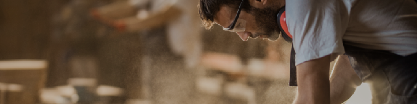 Focused craftsman sanding a live edge slab, highlighting the handmade quality of reclaimed wood furniture.