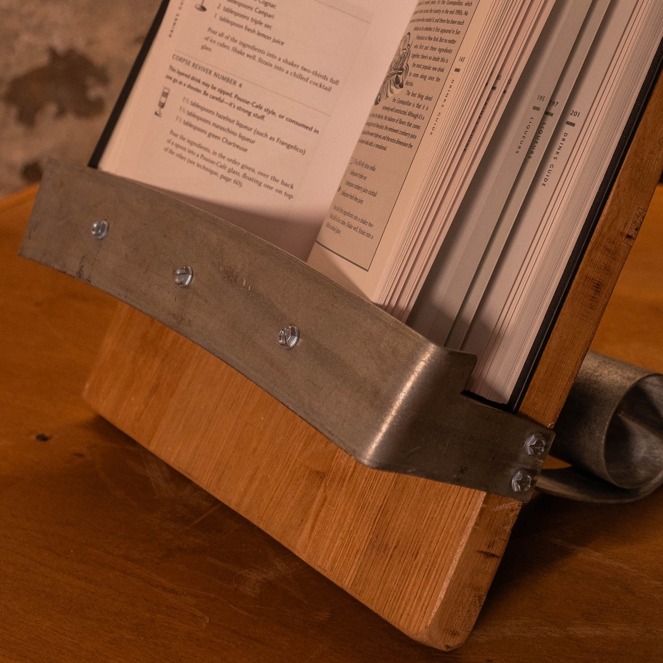 Close-up of the steel-hoop cradle on a reclaimed wood book stand holding an open book.