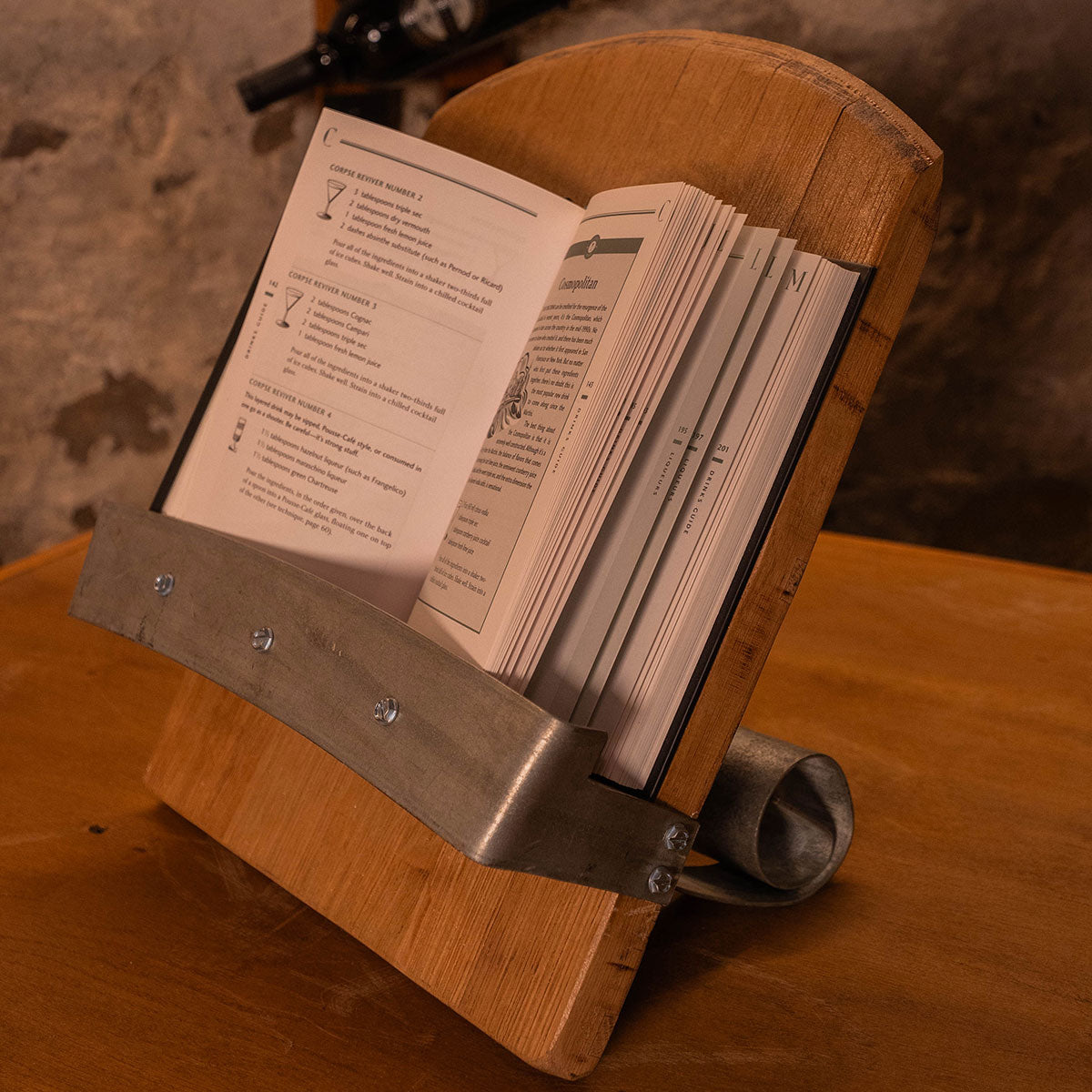 Reclaimed wood book stand with steel hoop cradle holding an open recipe book on a countertop.