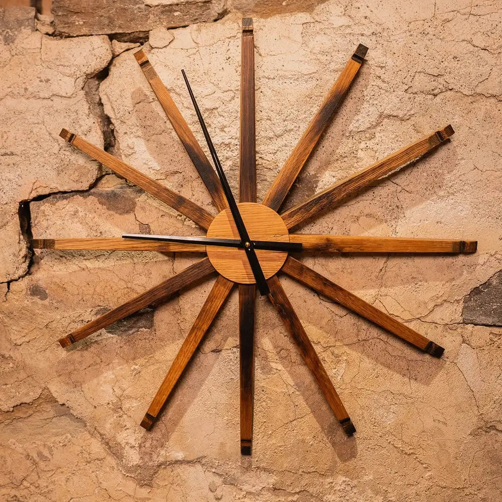 Large 24-inch wall clock handmade from reclaimed bourbon barrel staves, mounted on a textured stone wall.