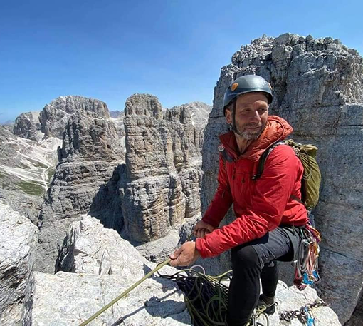 Artisan sitting on mountain rocks with woodworking tools, representing heritage craftsmanship.