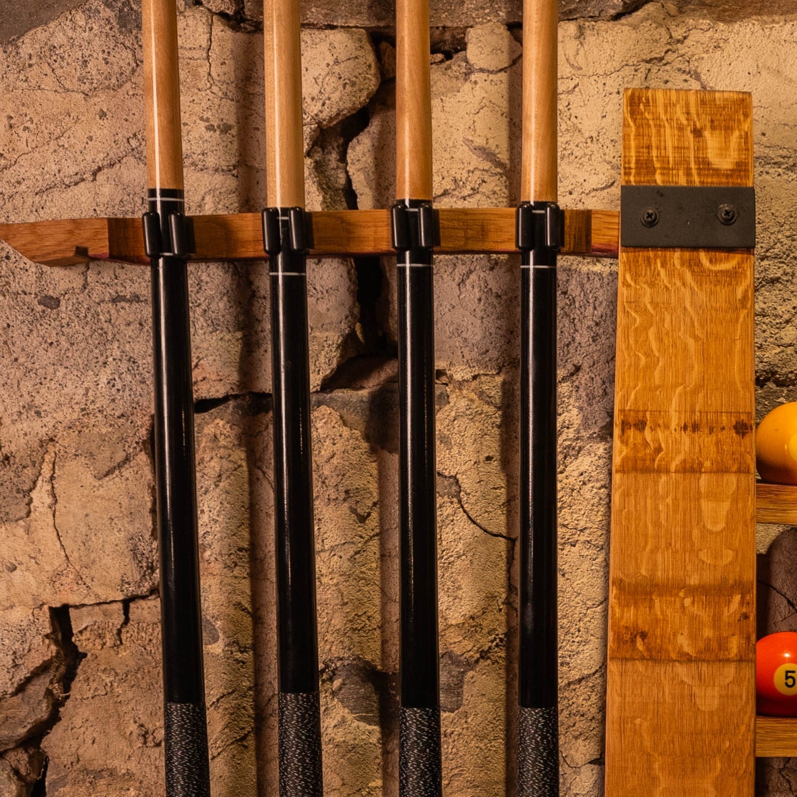 Close-up of snap-in cue clips securing pool cues on reclaimed barrel stave rack