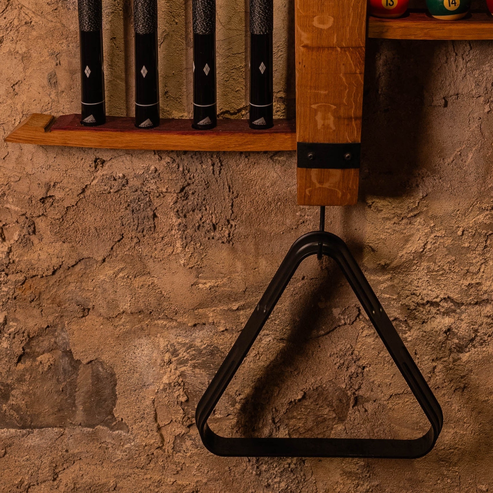 Angled view of wall-mounted cue and ball rack showing recessed lower alignment shelf