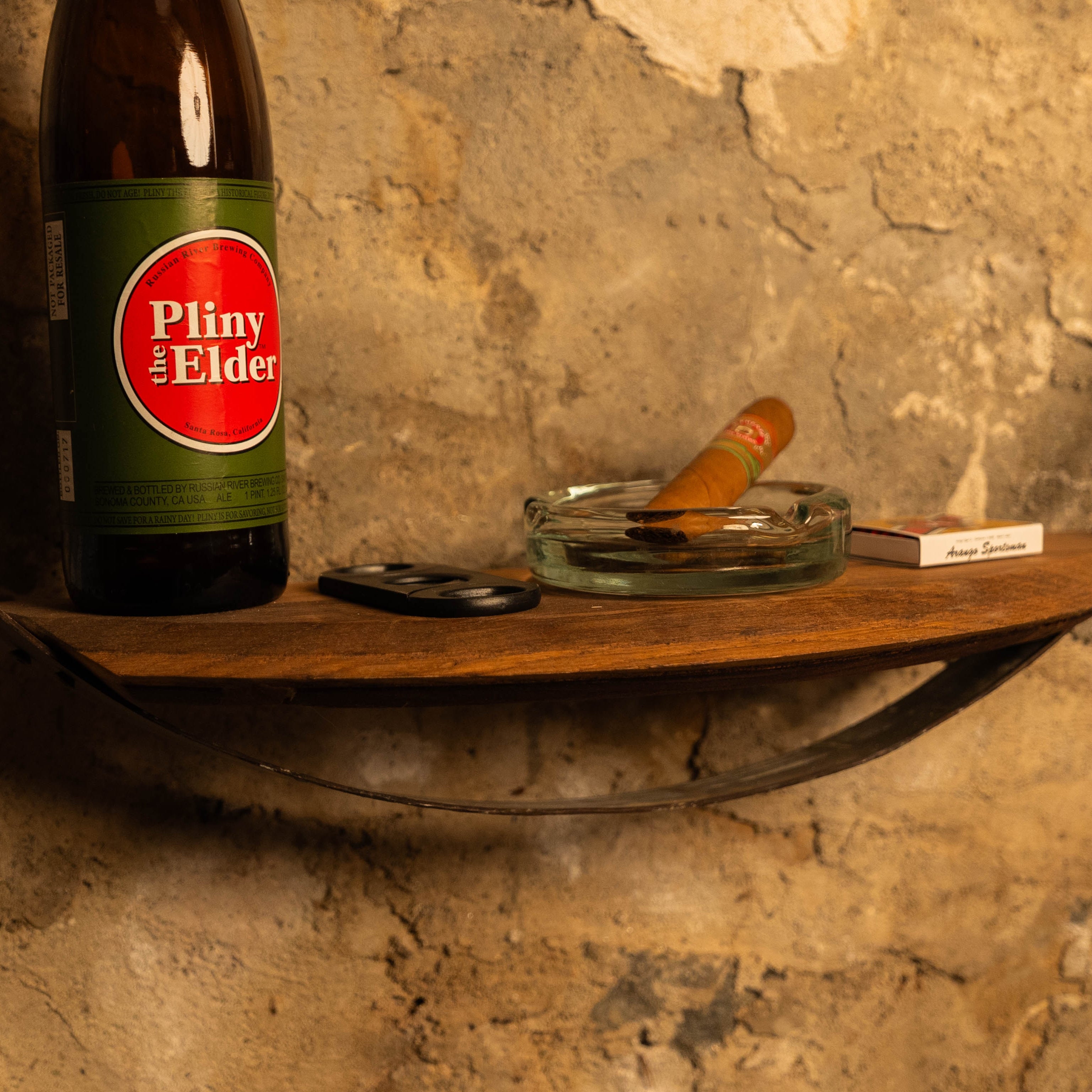 Close-up of the reclaimed barrel-hoop wall shelf showing the inset wooden half-moon shelf holding small items.