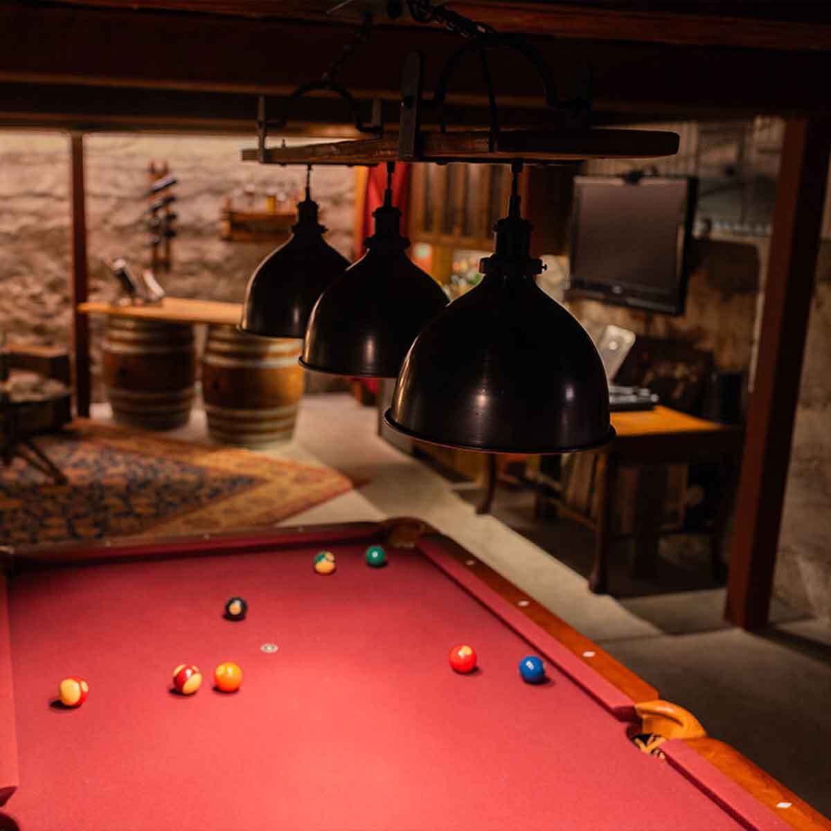 Pool table light fixture over a red velvet pool table in a home bar environment. Showing dimmed light for mood.