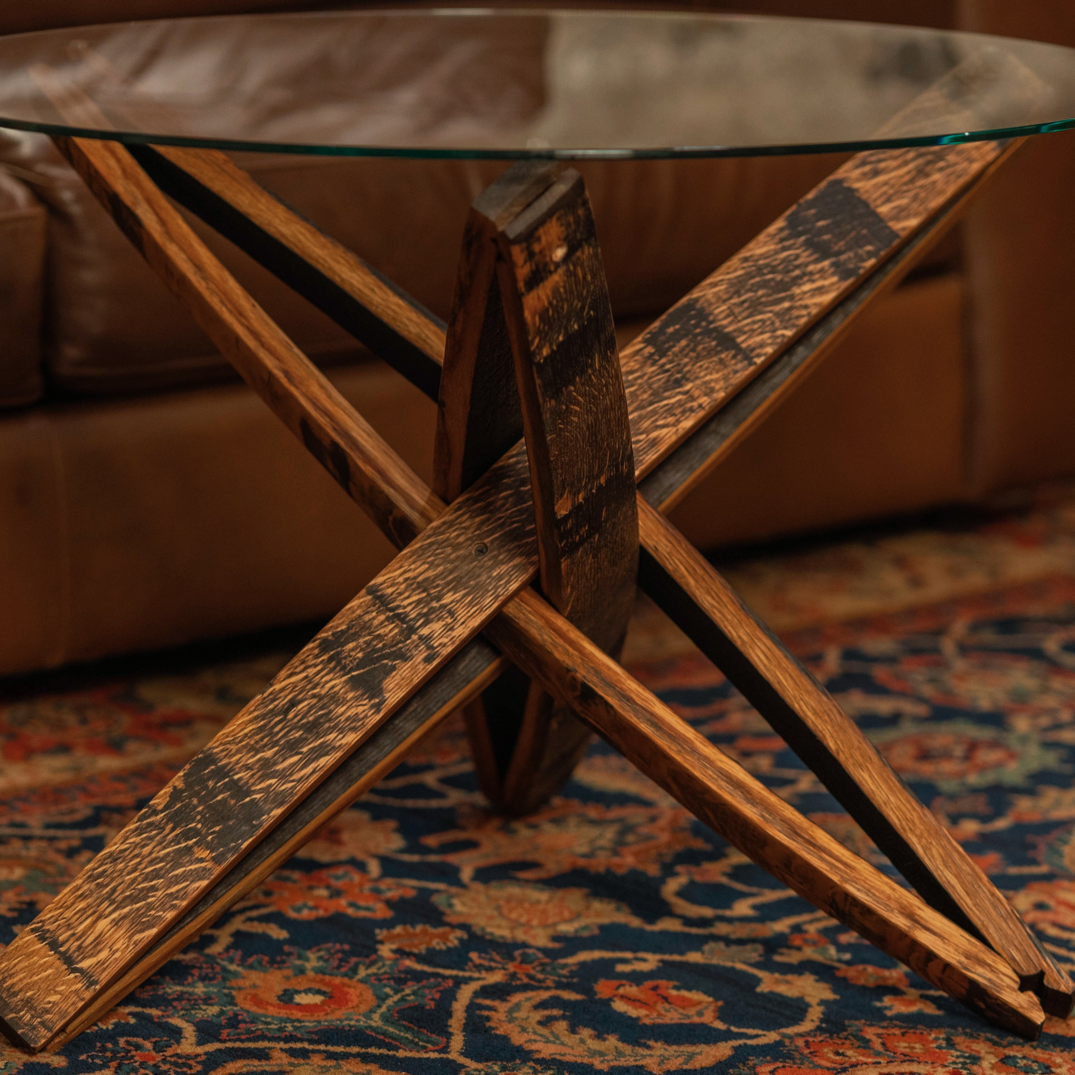 Close-up of the Stavv™ Whiskey Barrel Coffee Table base, showing the interlocking reclaimed barrel staves and rounded glass top.