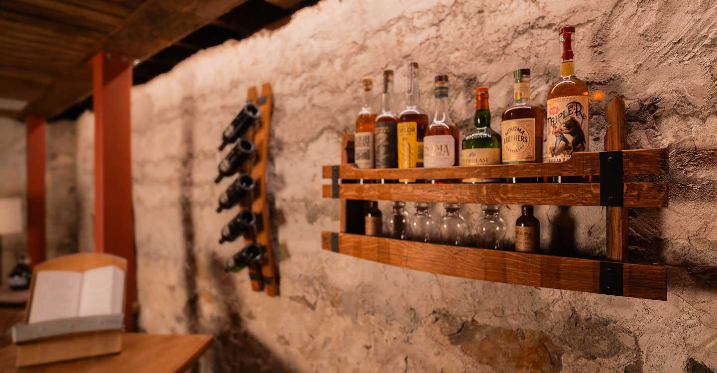 Wall bar shelf made of whiskey barrel staves, in a room full of rustic home decor.