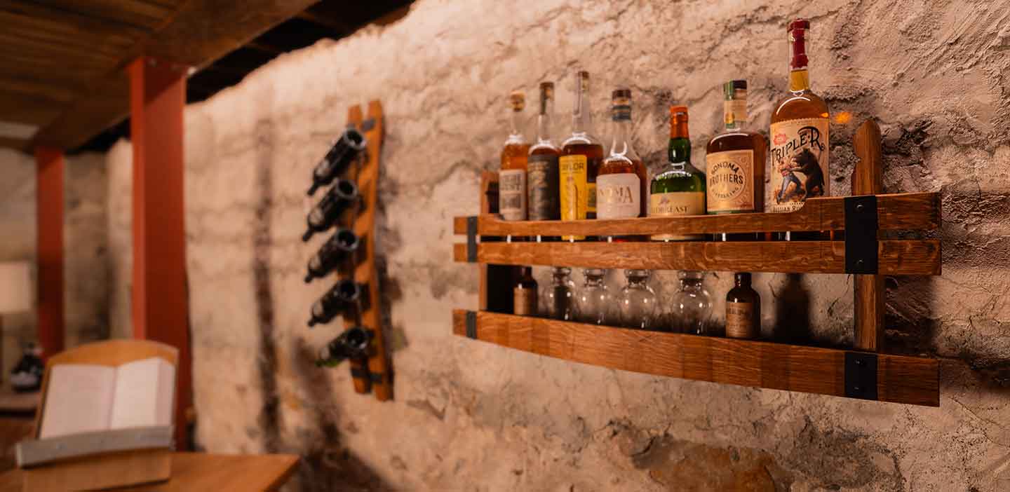 Wall bar shelf made of whiskey barrel staves, in a room full of rustic home decor.