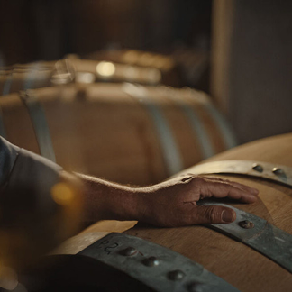 Close-up of stacked whiskey barrels, showing reclaimed material origin.