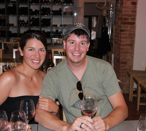 Two artisans posing inside rustic workshop surrounded by wood and barrels.