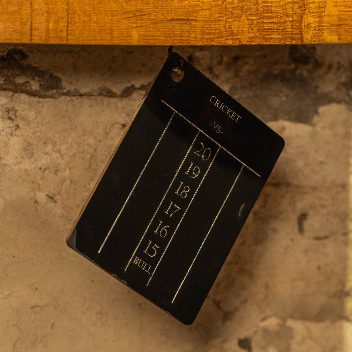 Cricket scoring chalkboard hanging against the wall below the dart backboard.