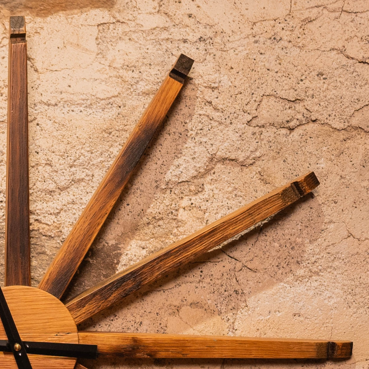 Close-up of charred bourbon barrel staves forming the spokes of a handcrafted rustic wall clock.