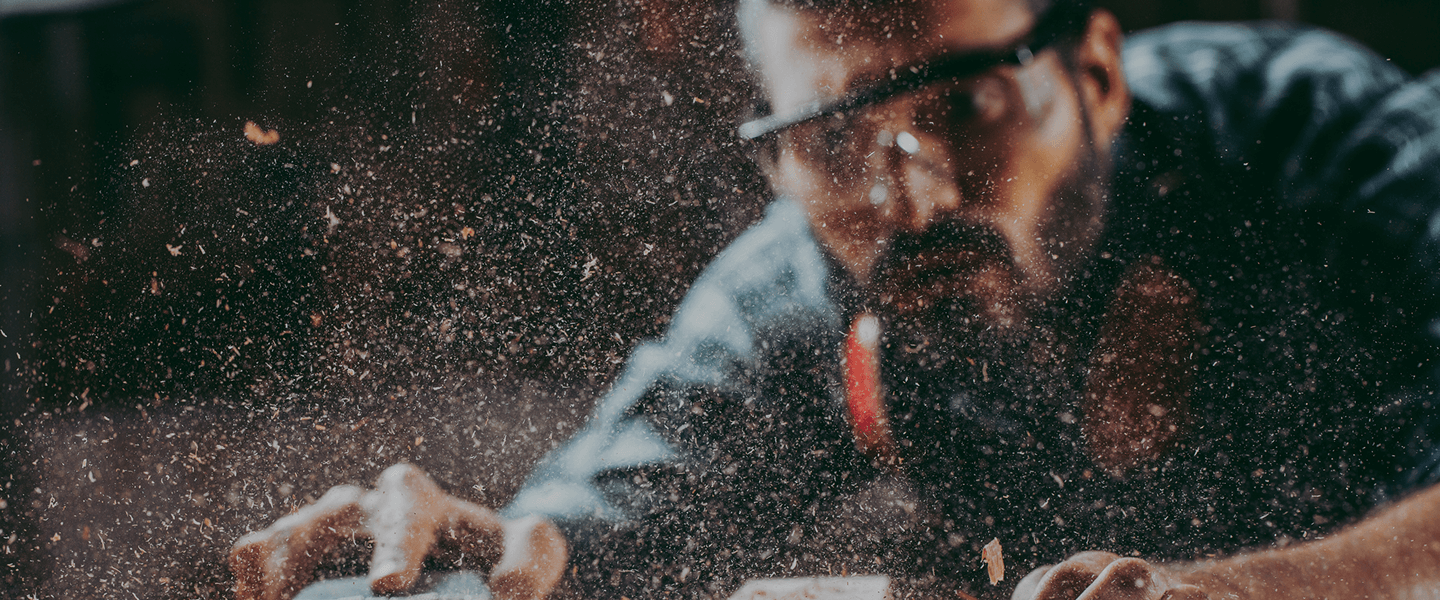 Close-up of a craftsman sanding reclaimed wood at the workbench, showcasing skilled craftsmanship.