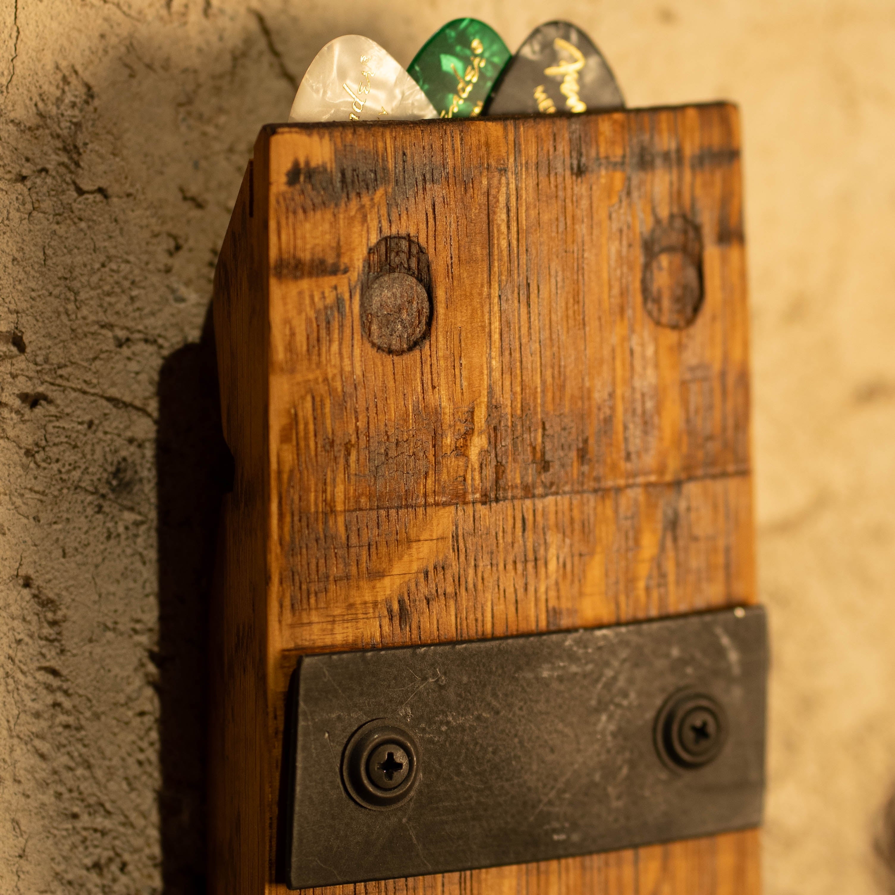 Close-up of a reclaimed wood guitar wall mount with pick storage at the top.