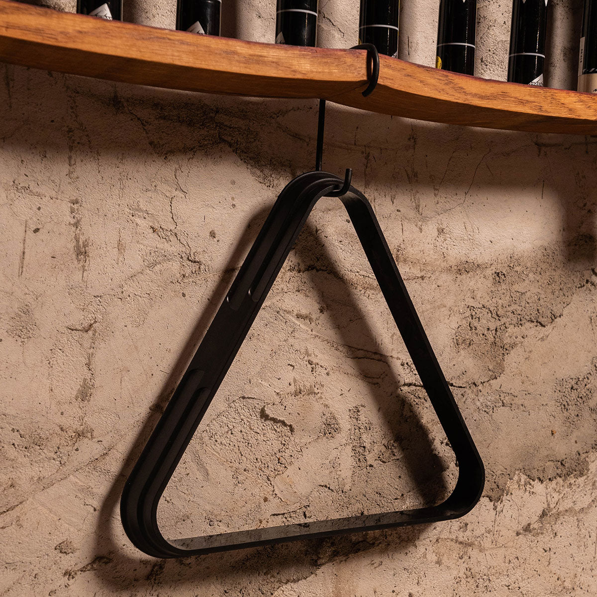 Detail of hanging triangle rack stored beneath wall-mounted pool cue rack