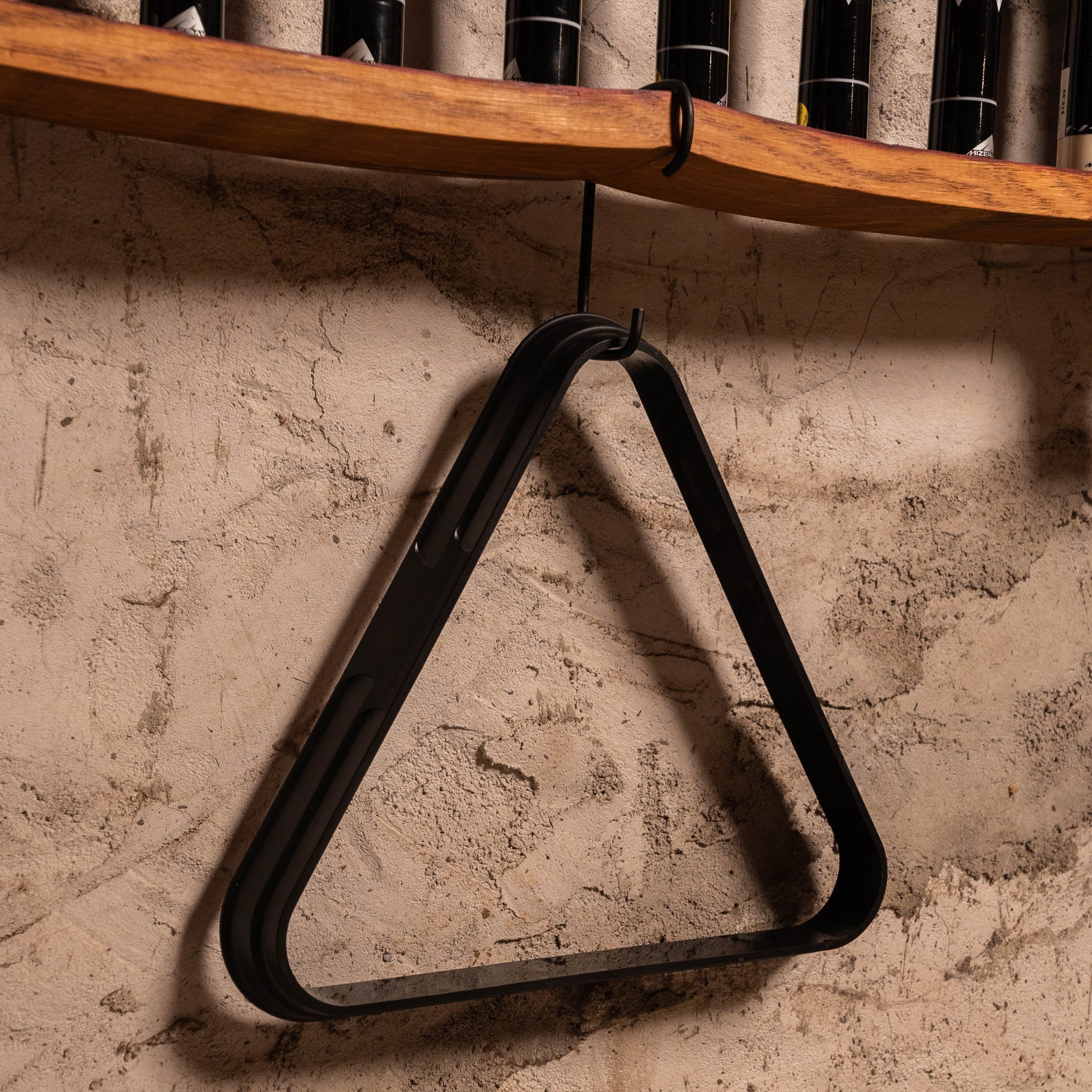 Detail of hanging triangle rack stored beneath wall-mounted pool cue rack