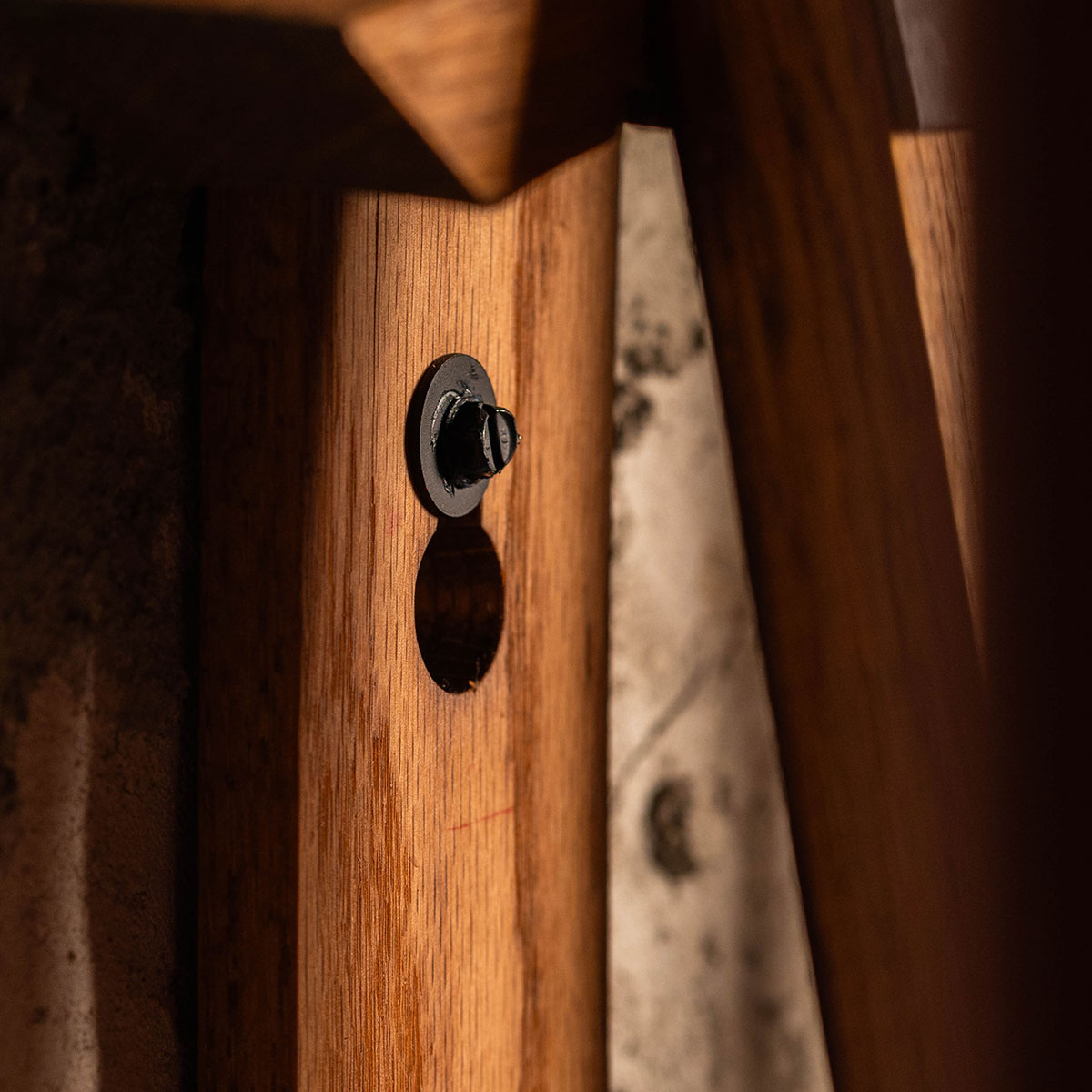 Close-up of recessed wall-mount hardware on reclaimed barrel stave pool cue rack