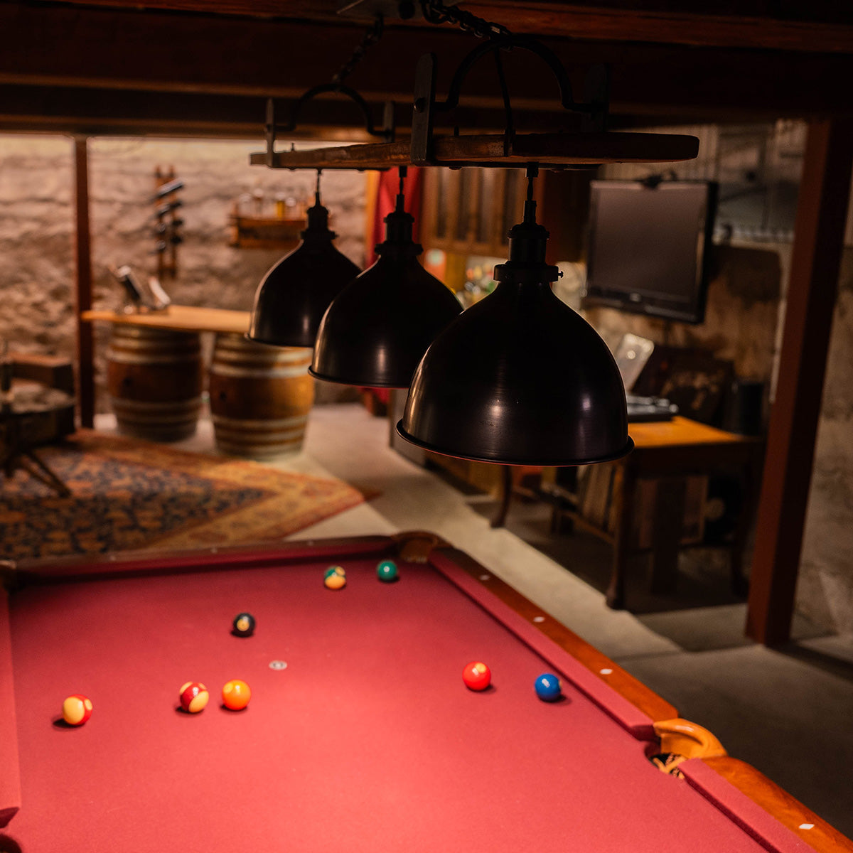 Pool table light fixture over a red velvet pool table in a home bar environment. Showing dimmed light for mood.